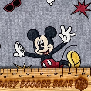 Pu&ograve; includere: Tessuto grigio con un motivo ripetitivo di Topolino in varie pose. Topolino indossa i suoi pantaloncini rossi e le scarpe gialle. Il tessuto presenta anche stelle rosse, punti bianchi e fulmini gialli.