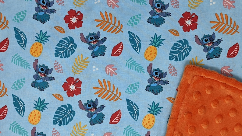 May include: A blue and orange baby blanket with a repeating pattern of Stitch from Lilo & Stitch wearing a grass skirt and dancing. The pattern also includes pineapples, hibiscus flowers, and tropical leaves.