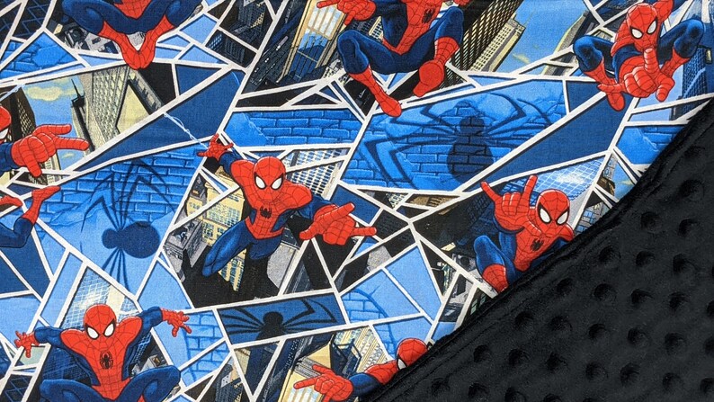 K&ouml;nnte beinhalten: Ein Stoff mit einem sich wiederholenden Muster von Spider-Man in Actionposen. Das Design beinhaltet blaue, rote und wei&szlig;e Farben, mit einem geometrischen Hintergrund und einem schwarzen, strukturierten Stoff auf der rechten Seite.