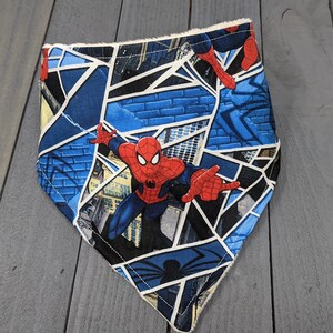 K&ouml;nnte beinhalten: Ein blau-wei&szlig;es Bandana mit einem Spider-Man-Design. Das Bandana hat ein geometrisches Muster mit Bildern von Spider-Man in Aktion. Die Kanten sind mit einem wei&szlig;en Besatz versehen. Dieses Accessoire ist f&uuml;r Haustiere geeignet.