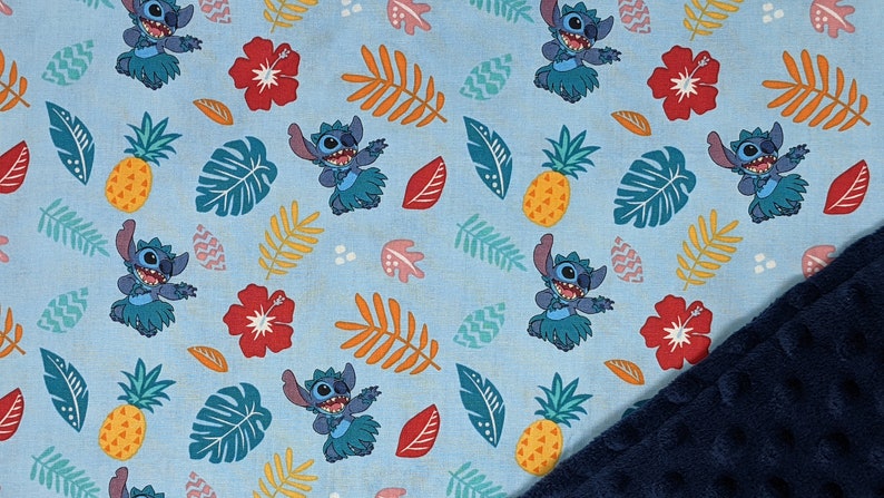 May include: Blue fabric with a repeating pattern of Stitch from Lilo & Stitch wearing a grass skirt, pineapples, hibiscus flowers, and tropical leaves.