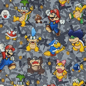 May include: Fabric featuring a repeating pattern of colorful cartoon characters, including Mario, Koopa Troopas, and Boos, set against a gray camouflage-style background. Gold coins and other game elements are also scattered throughout the design.