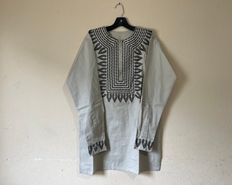 May include: A light gray long-sleeved shirt with a black embroidered design around the neckline.