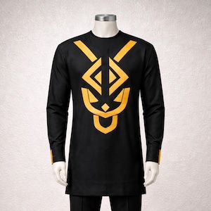 May include: Black long-sleeve shirt with a gold geometric design on the front. The shirt has a crew neck and gold accents on the cuffs. The shirt is displayed on a mannequin. This shirt is part of a traditional African clothing collection.