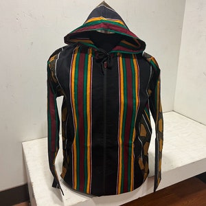 Pu&ograve; includere: Una giacca nera con cappuccio e chiusura a zip. La giacca ha un motivo a righe in rosso, verde e giallo.