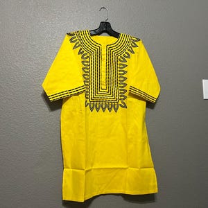 May include: A yellow short-sleeved shirt with a black geometric design around the neckline.