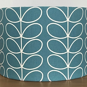 May include: Teal fabric lampshade with a white leaf pattern. The cylindrical lampshade features a repeating design of stylized leaves, creating a modern and decorative element for home lighting. The shade is suitable for a table or floor lamp.