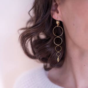 May include: Gold dangle earrings with a series of graduated circles and a small leaf charm.