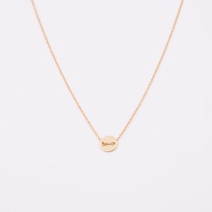 Peut inclure: Un collier délicat en chaîne dorée avec un petit pendentif rond sur lequel est inscrit le mot "Love".