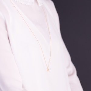 Peut inclure: Un collier en chaîne dorée avec un petit pendentif en forme de larme.