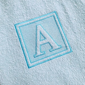 May include: A light blue towel with a white embroidered letter A in a blue square.