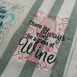 May include: Embroidered kitchen towel with a green and white striped background. The towel features a pink wine glass with the text "There is always time for a glass of wine".
