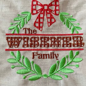 May include: Embroidered wreath with green leaves, a red and white checkered bow, and the text "The Wisener Family".