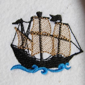Puede incluir: Diseño bordado de un barco negro con velas doradas sobre un fondo blanco. El barco navega sobre olas azules.