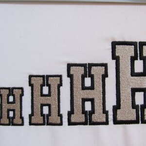May include: A series of five embroidered letter H characters arranged in increasing size from left to right. Each letter features a light beige center with a thick black stitched border, presented on a plain white fabric background.