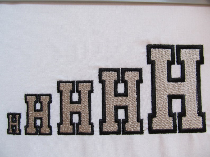 May include: A series of five embroidered letter H characters arranged in increasing size from left to right. Each letter features a light beige center with a thick black stitched border, presented on a plain white fabric background.
