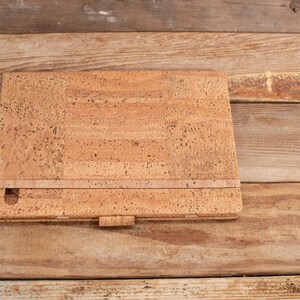 May include: A cork notebook with a brown leather strap and a cork cover.