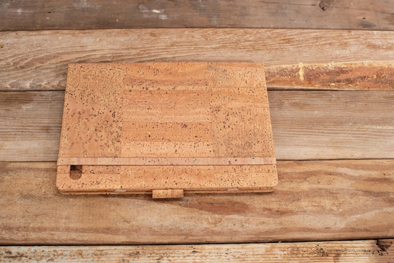May include: A cork notebook with a brown leather strap and a cork cover.