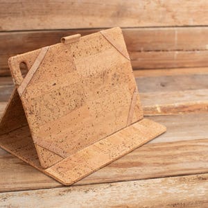 May include: A brown cork tablet case with a fold-over flap and a textured cork surface.