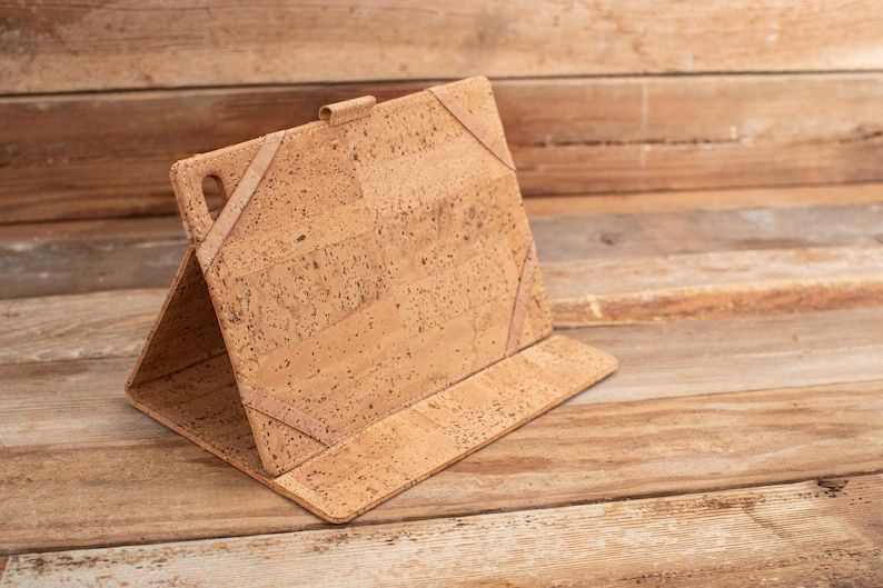 May include: A brown cork tablet case with a fold-over flap and a textured cork surface.
