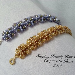 May include: Two beaded bracelets, one in shades of purple and gold, and the other in gold and cream. The bracelets are on a white surface and the text "Sleeping Beauty Bracelet Elegance by Renee 2015" is below them.