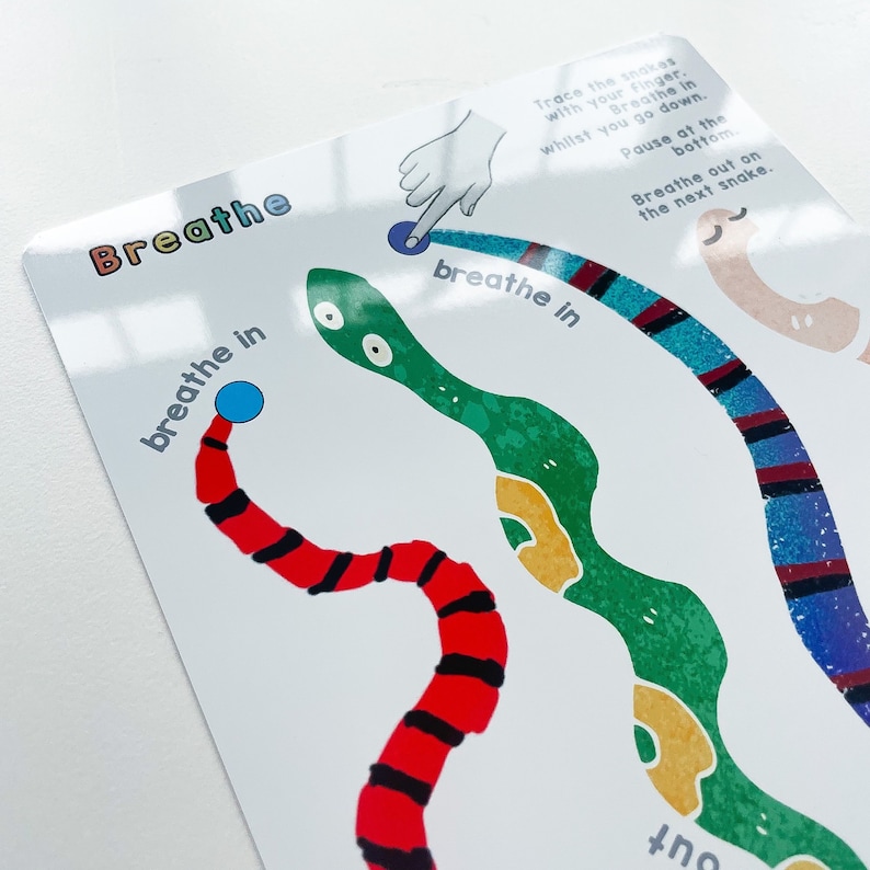 Puede incluir: Una tarjeta blanca con una serpiente verde, azul y roja dibujada en ella. La tarjeta tiene las palabras "Breathe" y "breathe in" escritas en ella. La tarjeta est&aacute; dise&ntilde;ada para ayudar a los ni&ntilde;os a aprender a respirar.