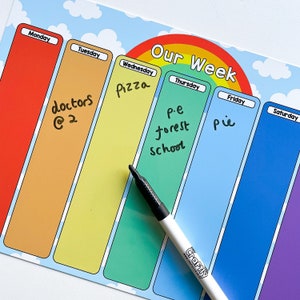 Puede incluir: Un planificador semanal colorido con un arcoíris en la parte superior. Los días de la semana están listados en la parte superior: Lunes, Martes, Miércoles, Jueves, Viernes, Sábado. Cada día tiene un espacio para escribir actividades. Las palabras "Nuestra Semana" están escritas en un arcoíris en la parte superior del planificador.