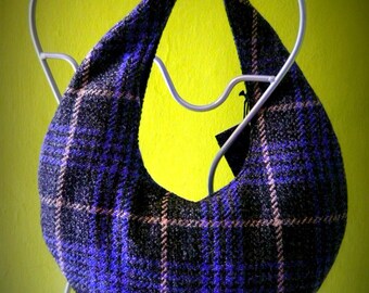 May include: A purple and black plaid fabric handbag with a crescent shape hanging on a silver hanger.