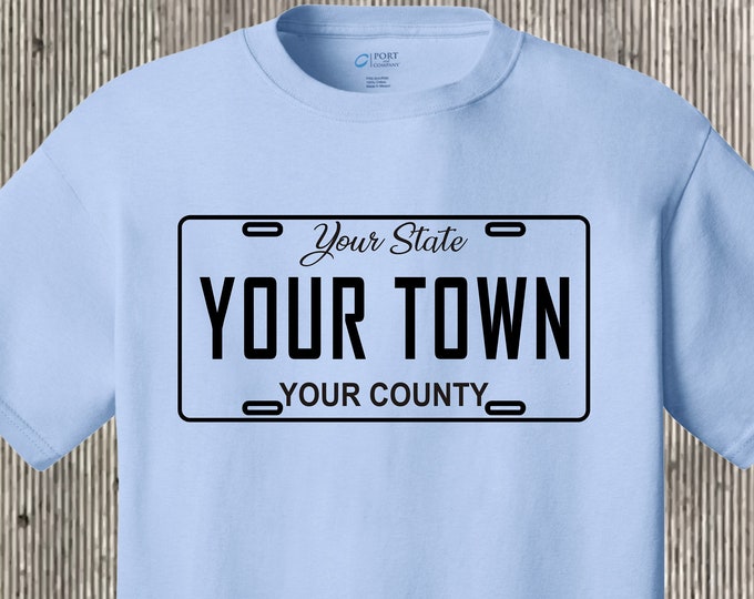 Your town (community, city, etc) license plate car tag T shirt also featuring your state and county - any place!  Many colors to choose from