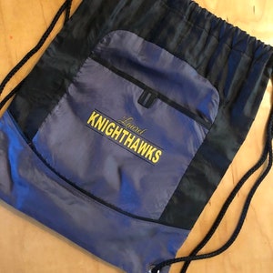 May include: A black and gray drawstring bag with a zippered pocket. The bag has a yellow embroidered logo that says "Laurel Knighthawks".