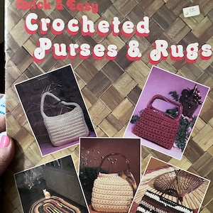Op de afbeelding: Een boekomslag met de titel "Quick & Easy Crocheted Purses & Rugs". De omslag toont foto's van gehaakte handtassen en tapijten in verschillende kleuren, waaronder beige, rood en bruin.