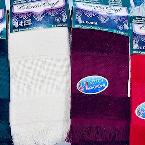Peut inclure: Quatre serviettes pour les doigts de différentes couleurs : vert, blanc, bordeaux et rouge. Chaque serviette porte une étiquette indiquant « Charles Craft Cross Stitch Fingertip Towel 14 Count 100 % Cotton/Algodon E-Z Stitch » et un logo indiquant « E-Z Stitch Border ».