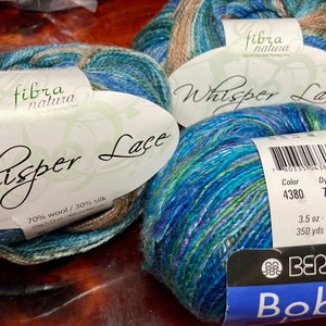 May include: Two skeins of blue, green, and brown yarn labeled "Whisper Lace" with the brand name "Berroco Boboli" and the text "70% wool / 30% silk" and "3.5 oz - 100 g, 350 yds - 320 m".
