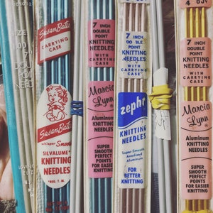 Könnte beinhalten: Nahaufnahme von vier Packungen Stricknadeln. Die Packungen sind alle in verschiedenen Farben und haben verschiedene Marken. Die Nadeln sind alle 17,8 cm lang und aus Aluminium. Die Packungen enthalten auch Tragetaschen.