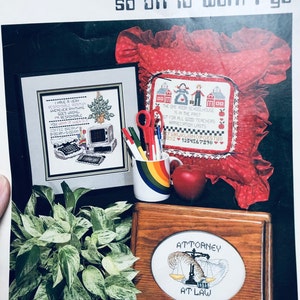 May include: A cross-stitch pattern booklet with a red, white, and blue color scheme. The cover features a cross-stitch design of a one-room schoolhouse with the text "The one room schoolhouse is in the past but for all good teachers appreciation lasts".