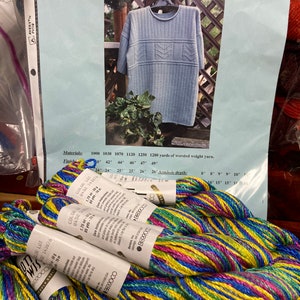 May include: A close-up of several skeins of multi-colored yarn in shades of blue, green, yellow, and pink. The yarn is labeled "Berroco".