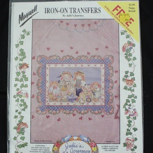 May include: Iron-on transfer sheet featuring a family of bunnies in a pink frame with a blue and white polka dot border. The transfer sheet is part of a set of 24 blue line embellishment transfers. The image is titled "Bunny Family Portrait" and is from the "Julie's Journey" collection.