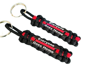 May include: Two black paracord keychains with red stripes and a black metal tag that reads "Everyone Goes Home".