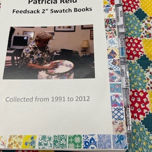 Puede incluir: Un libro blanco con el título "Patricia Reid Feedsack 2" Swatch Books" y el texto "Collected from 1991 to 2012". El libro tiene un borde colorido con pequeños cuadrados de tela.