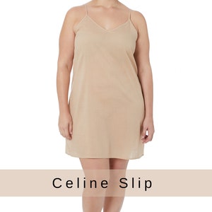 May include: A beige slip dress with thin straps and a V-neckline. The dress is knee-length and has a simple, classic design. "Celine Slip" is written in black text on a beige background.
