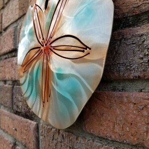 Pu&ograve; includere: Un decoro da parete in metallo a forma di dollaro di sabbia con uno schema di colori turchese e rame. Il dollaro di sabbia ha un design in rilievo di una stella a cinque punte.