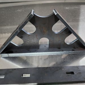 May include: A metal triangle with cutouts, possibly used for woodworking or construction.