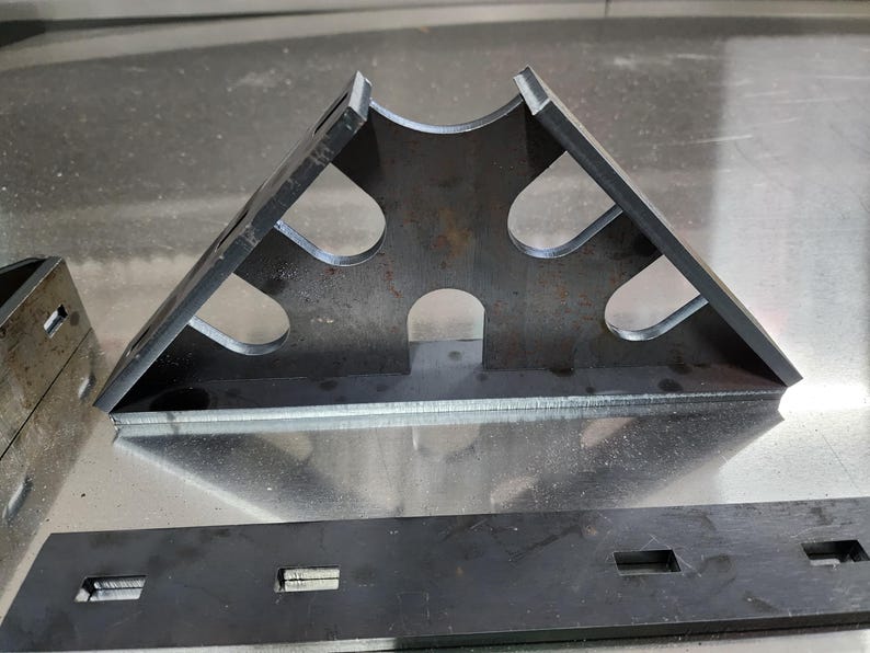 May include: A metal triangle with cutouts, possibly used for woodworking or construction.