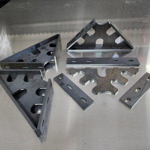 May include: A set of metal brackets and plates with cutouts. The brackets are triangular and have multiple holes. The plates are rectangular and have a series of holes along the edges.