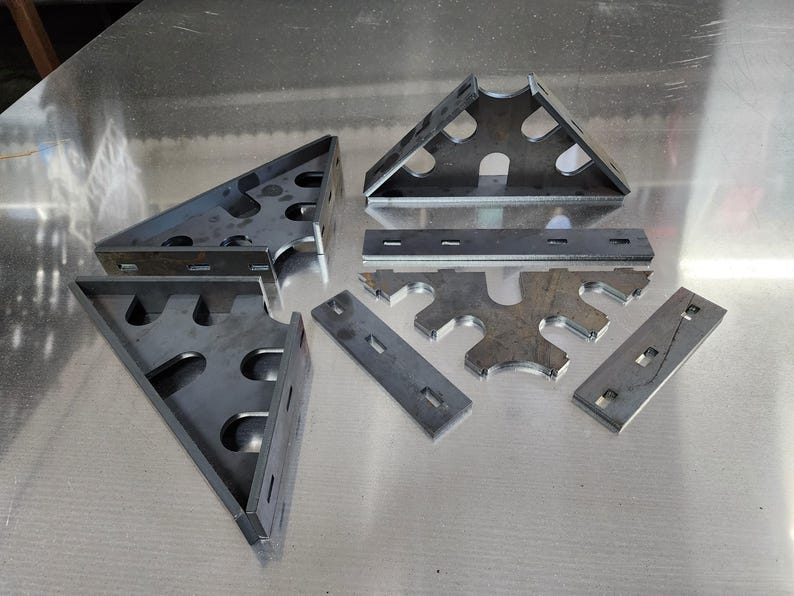 May include: A set of metal brackets and plates with cutouts. The brackets are triangular and have multiple holes. The plates are rectangular and have a series of holes along the edges.