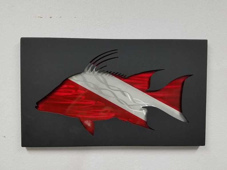 Puede incluir: Una bandera de buceo roja y blanca est&aacute; recortada sobre un fondo negro. La bandera tiene la forma de un pez.