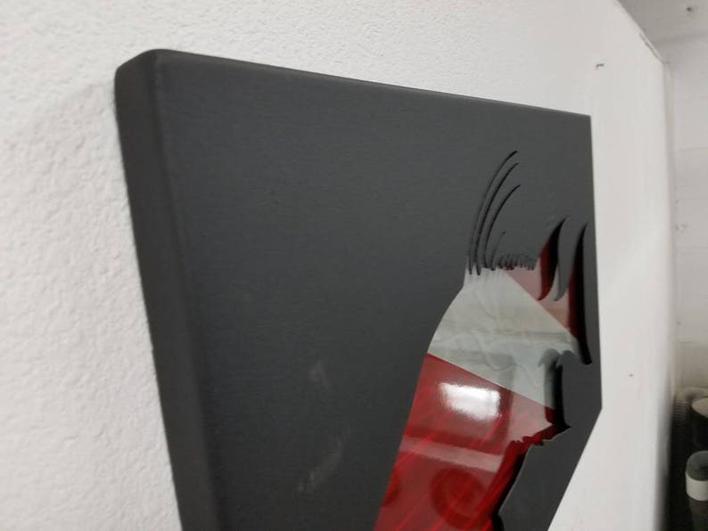 Puede incluir: Arte de pared de metal negro con un dise&ntilde;o recortado de un pez. El pez es rojo y blanco con un contorno negro. El arte est&aacute; montado en una pared blanca.