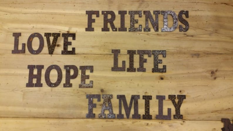May include: A wooden sign with the words "LOVE", "HOPE", "FRIENDS", "LIFE", and "FAMILY" written in metal letters.