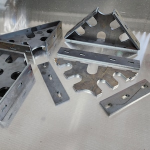 May include: A set of metal brackets and strips with cutouts. The brackets are triangular and have multiple holes. The strips are rectangular and have a series of slots.