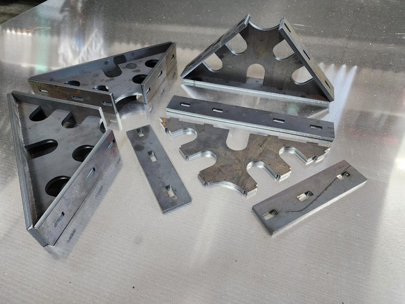 May include: A set of metal brackets and strips with cutouts. The brackets are triangular and have multiple holes. The strips are rectangular and have a series of slots.